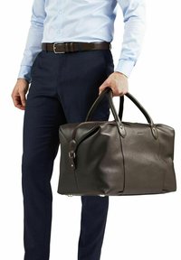 Brun läder resväska med texturerad yta, två robusta handtag och dragkedjestängning. Accentuerad med metallbeslag och skyddsfötter på basen.