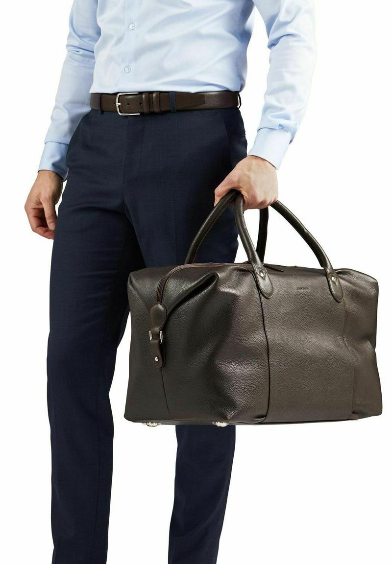 Brun läder resväska med texturerad yta, två robusta handtag och dragkedjestängning. Accentuerad med metallbeslag och skyddsfötter på basen.