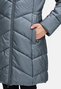 Gray padded winter coat featuring a chevron pattern, front zipper, and side pocket with a loop detail for easy storage.