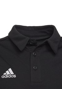 Schwarzes Polohemd aus glattem Stoff, mit einem klassischen Kragen, drei schwarzen Knöpfen und einem weißen Adidas-Logo auf der linken Brust.