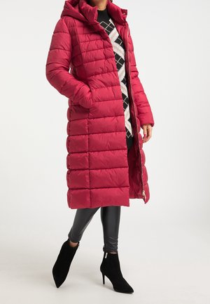 Frau trägt langen roten Steppmantel, schwarz-weißes Rautenmuster-Pullover, schwarze Lederleggings und schwarze Stiefeletten mit Absatz.