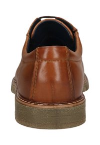Chaussure en cuir marron avec une texture lisse, un talon arrondi, des coutures décoratives et une semelle en caoutchouc contrastante. La vue arrière met en valeur la courbure de la chaussure.