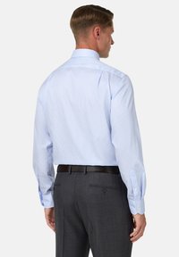 Gai zils svītrains krekliņ�š ar norādītu apkakli, poga nolaistām aprocēm un gludu auduma tekstūru, valkāts ar tumši pelēkiem biksēm un melnu jostu.