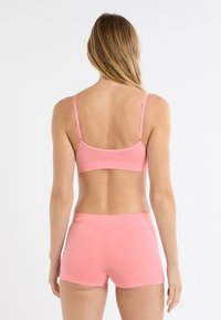 Bralette rosa in cotone con spalline regolabili e boyshorts abbinati, caratterizzati da un design senza cuciture e tessuto morbido ed elastico.