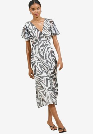 Zebra-kuosi mekko kevyestä kankaasta, jossa ovat läpikuultavat lyhyet hihat, syvä V-pääntie ja midi-pituus, sekä suloinen ja ilmava siluetti.
