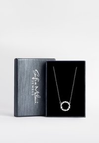 Collana d'argento in una scatola foderata di velluto nero. Presenta un pendente circolare con pietre trasparenti e una delicata catena. La scatola ha una finitura in argento texture.