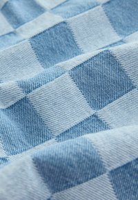 Világoskék farmeranyag kockás mintával; texturált szövet, eltérő kék árnyalatokkal, amelyek finom mélységérzetet keltenek.