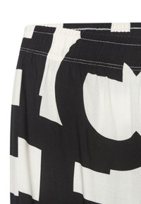 Black and white patterned fabric with large geometric shapes. Elastic waistband with gathered texture. Smooth, lightweight material.