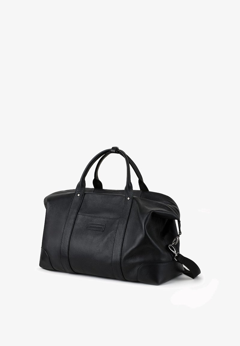 Czarna skórzana torba podróżna z dwoma górnymi uchwytami, bocznym zamkiem błyskawicznym, teksturowanym wykończeniem i odpinanym paskiem na ramię. Prosty, przestronny design.