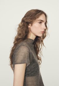 Kortemouwen top met aansluitende pasvorm van doorschijnende bruine stof, met een hoge halslijn en een gladde textuur, met subtiele kleurvariaties.