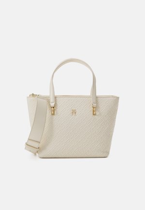 White textured handbag with dual top handles, gold hardware accents, and an adjustable strap. Features a patterned surface and logo detail.
