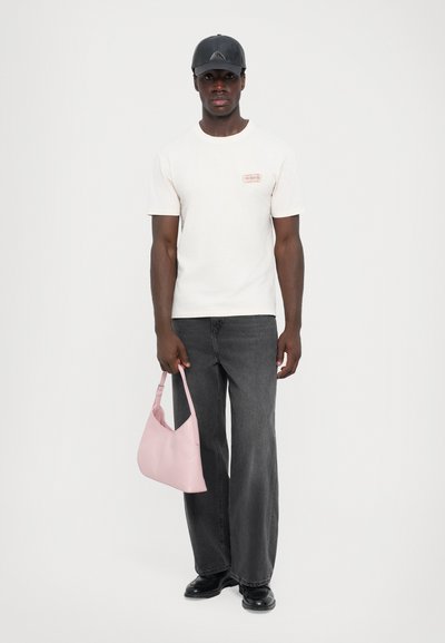 White cotton t-shirt with a small logo patch, black wide-leg jeans, pink leather handbag with a rounded shape, and black shoes.