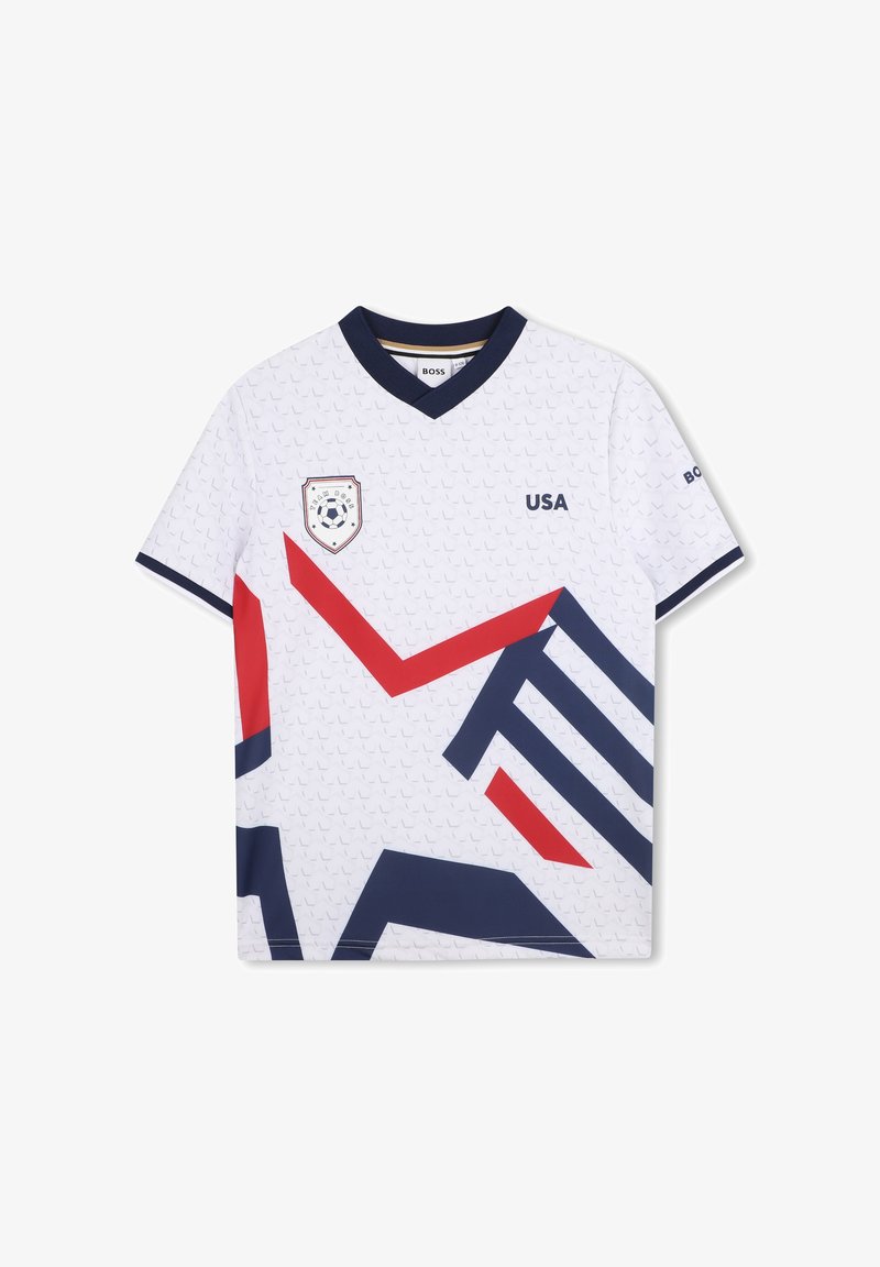 Maillot de football blanc avec des motifs géométriques rouges et bleu marine. Il comporte un col en V, des manches courtes et un emblème des États-Unis sur le côté gauche de la poitrine.