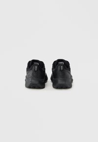 Μαύρα αθλητικά παπούτσια με υφή στην επάνω επιφάνεια, επενδεδυμένο γιακά και στρογγυλεμένη σόλα. Περιλαμβάνουν ξεχωριστό λογότυπο και ελάχιστες λεπτομέρειες στη φτέρνα.