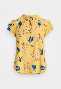 Gul blus med korta ärmar och blommönster i blått och rosa. Har en samlad halsringning och volangärmar. Mjuk tygtextur.
