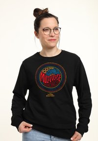 Sudadera negra con un gráfico circular multicolor que incluye el texto "Doctor Strange: Multiverse of Madness". Corte clásico con mangas largas.