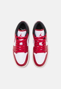 Paire de baskets basses rouges, blanches et noires avec des lacets rouges et un logo Jumpman rouge sur la languette blanche, vue de dessus.