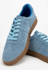 Helleblaue Wildledersneaker mit passenden Schnürsenkeln, runder Zehenpartie, flacher Sohle und strukturiertem Gummiaußensohle. Keine sichtbaren Logos oder Akzente.