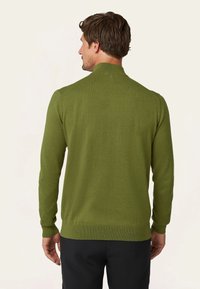 Groene gebreide trui met lange mouwen en een hoge kraag. Beschikt over een geribbelde zoom en manchetten, gemaakt van zachte stof, met een gladde textuur.