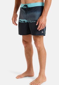 Shorts de bain pour hommes, dégradé de bleu foncé à noir avec une taille turquoise, cordon de serrage élastique, logo Quiksilver, longueur au-dessus du genou.