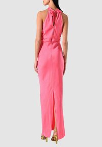 Abito lungo in satin rosa con collo alto, schiena scoperta, dettaglio con fiocco e spacco alto sulla coscia. Presenta chiusure con bottoni sulla schiena.