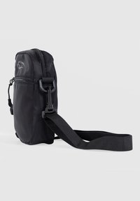 Black nylon crossbody bag with zip closure, adjustable strap, and logo detail. Features a compact shape and textured surface.