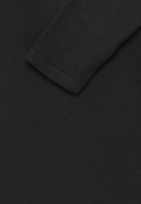 Pull noir en tricot montrant un gros plan sur la texture et les détails du tissu, avec un bord de manche visible. Lisse, épaisseur moyenne.