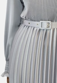Abito plissettato in satin grigio chiaro, dotato di una cintura coordinata con hardware argentato e un sottile dettaglio di texture nel tessuto.