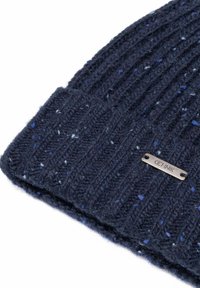 Ciemnoniebieska dziana czapka z prążkowaną teksturą i drobnymi jasnoniebieskimi oraz szarymi plamkami, z metalową metką marki "CHNIK".