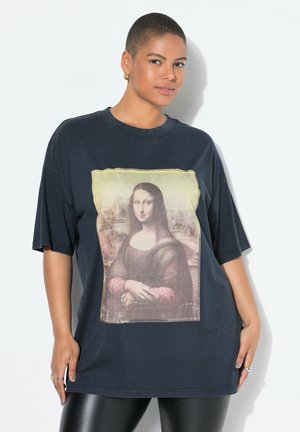 Camiseta negra de gran tamaño con estampado de la Mona Lisa en la parte delantera. Material de algodón con cuello redondo y mangas cortas.