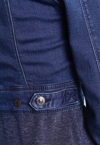 Jeansjacka i mörkblått, med knappstängning, kontrasterande sömmar och en lagerdesign med en melerad tyg under.