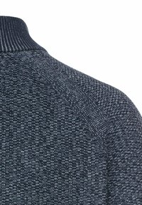 Dunkel gestrickter Pullover mit hohem Kragen, der ein strukturiertes Muster aufweist. Das Material wirkt weich, mit kontrastierenden Blautönen.