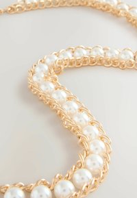Gold chain necklace featuring interwoven white pearls, with a smooth texture and shiny finish, showcasing a looped and linked design.