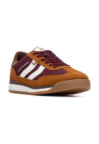 Zapatillas de ante marrón con acentos de tela burdeos, que presentan rayas blancas y cordones marrones. Diseño esbelto con una suela de goma texturizada.
