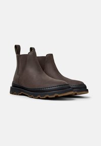 Bruine leren Chelsea-boots met elastische zijpanelen, ronde neus, zwarte rubberen zool en contrasterende gestructureerde randontwerp.