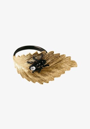 Anillo negro con un diseño texturizado de hoja dorada y una pequeña araña negra con una gema clara sobre la hoja.