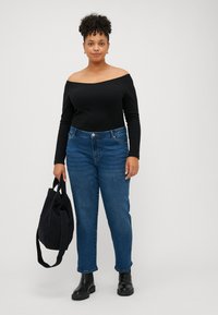 Top nero off-the-shoulder con maniche lunghe, abbinato a jeans blu dritti. Stivaletti neri alla caviglia e borsa a tracolla nera in tela.