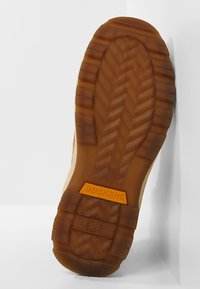 Semelle en caoutchouc marron avec un motif en zigzag, arborant un logo "Dockers" en relief orange. Le design présente une surface de grip texturée.
