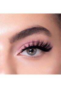 Närbild av ett öga med långa, tjocka svarta ögonfransar, rosa ögonskugga och ljus hy; iris är grå med bruna fläckar.