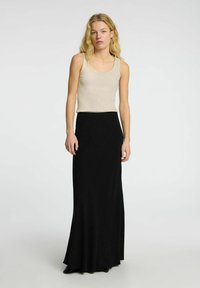 Zwarte maxi-jurk gemaakt van zachte stof, gecombineerd met een beige geribbelde tanktop. De outfit heeft een aansluitende taille en een vloeiende zoom.