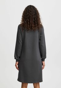 Graues Langarmkleid aus weichem Stoff, mit lockerer Passform, abgerundetem Saum und gerippten Bündchen. Schlichtes Design ohne sichtbare Muster.