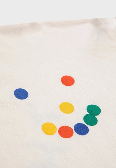Pamuk majica s krem pozadinom, koja sadrži šest šarenih krugova: plavi, crveni, žuti i zeleni, različitih veličina i pozicija.