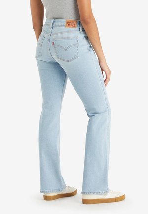 Ljusblå, utsvängda jeans i denim. Har hög midja, bakfickor med sömmar och en brun läderlapp vid midjan.