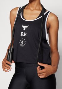 Svart linne med vita accenter, med logotyp och text. Modellen håller i ett svart hopprep och har svarta leggings.