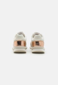 Vita sneakers med en metallisk roséguldaccent på hälen, texturerat tyg och en vadderad sula för komfort.