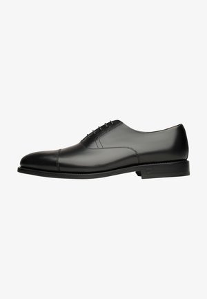 Schwarze Leder-Die Schuhe mit glatter Oberfläche, abgerundetem Zeh, minimalistischen Design und sechs Ösen für die Schnürung. Robuste schwarze Sohle.