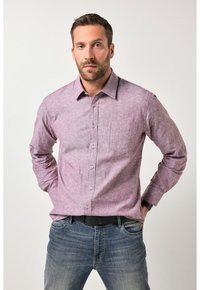 Rød- og hvidternet langærmet skjorte med knapper, lomme på venstre bryst, kombineret med blå jeans. Stoffet virker tekstureret.