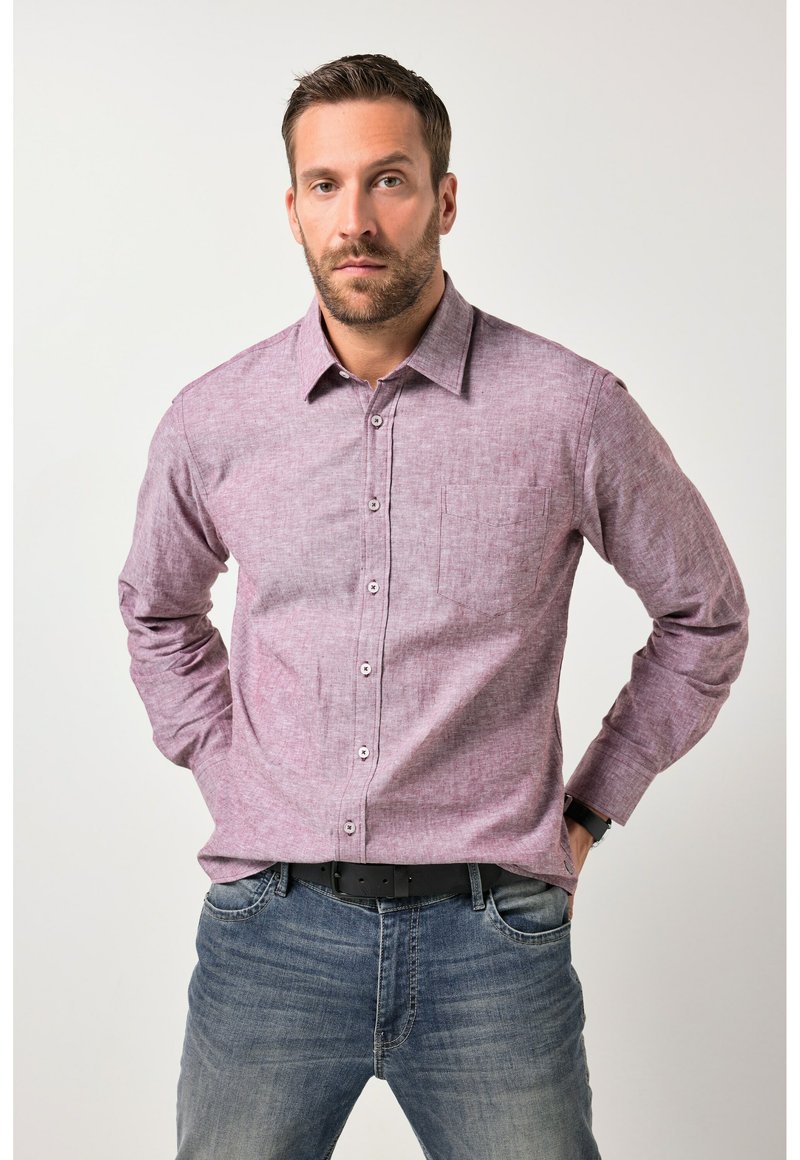 Rød- og hvidternet langærmet skjorte med knapper, lomme på venstre bryst, kombineret med blå jeans. Stoffet virker tekstureret.