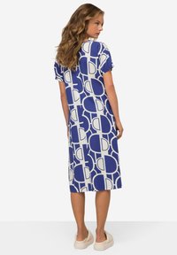 Modré a bílé vzorované šaty s krátkým rukávem a volným střihem, se geometrickým designem a dosahující délky do poloviny lýtek.