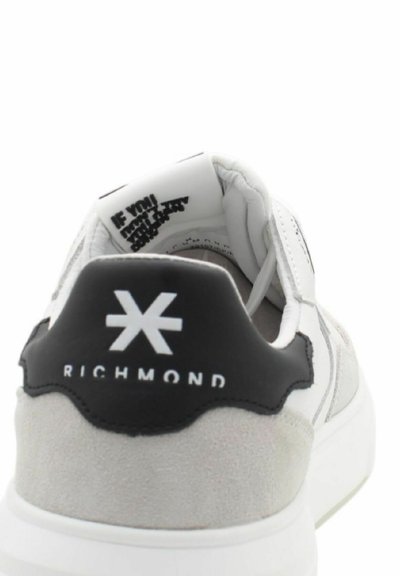 Sneaker bianca con accenti in suede grigio e pelle nera, con un logo sul tallone e colletto imbottito per il comfort.